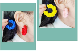 Detail of twisted C-shaped acrylic earrings in matte blue, red, yellow and pink colors