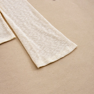 Détail de la manche en tricot blanc cassé avec maille fine sur fond en bois chaleureux