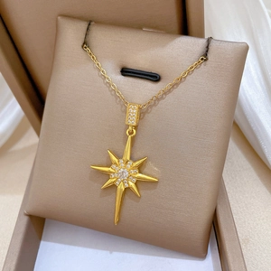 Detailed close-up of a gold starburst pendant necklace with crystals on a soft cushion