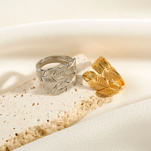 Detailed view of gold and silver feather-shaped open rings on a stone surface