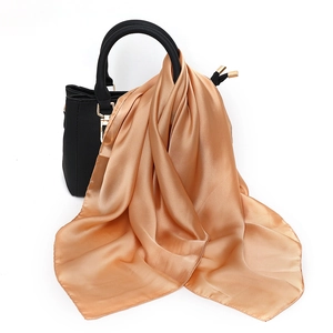 Champagne gold satin square scarf elegantly draped over a black leather handbag