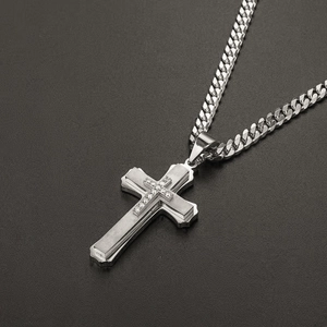 Detail of silver multilayered cross pendant with zircon stones on a cuban chain necklace