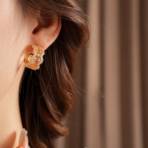 Close-up of golden C-shaped hoop earrings with sparkling cubic zirconia on a model