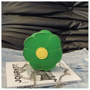 Detail of flower shaped green crossbody bag with yellow center and silver chain strap
