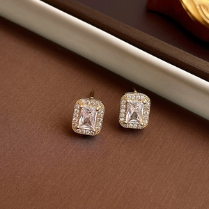 Close-up of golden square zircon halo earrings with rectangle crystal and small round stones