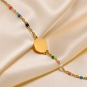 Detail of gold chain bracelet with colorful beads and round charm on champagne silk fabric