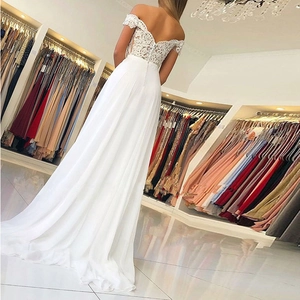 Elegant white off-shoulder lace wedding dress with an open back and flowing chiffon skirt
