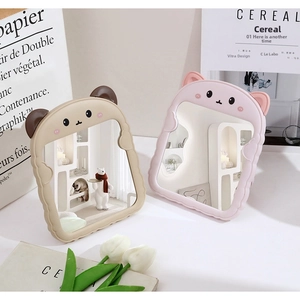 Detail view of cute cartoon bear and cat ears folding desktop makeup mirrors in cream and pink