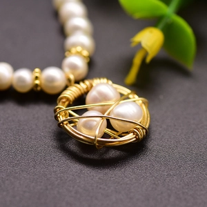 Handmade necklace with gold bird nest pendant holding three pearls on a pearl chain