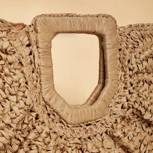 Close-up of the natural woven straw material and integrated rectangular handle on the beach bag