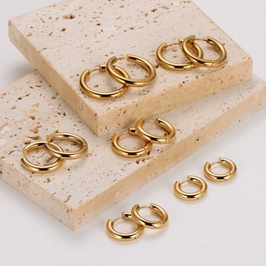 Polished 18K gold plated stainless steel hoop earrings in various sizes on stone steps