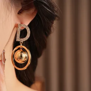 Elegance Gold D-Letter Hoop Earrings with Sphere Charm worn on ear for minimalist style