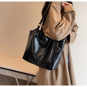 Detail of a large black soft leather tote bag with subtle oil wax texture for women