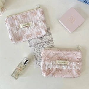 Close-up of floral lace coin purse with bow embroidery and satin texture details