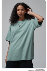 Detail of sage green oversized cotton t-shirt showing dropped shoulders and crew neck line