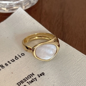 Close-up of a gold adjustable ring featuring an irregular white gemstone on a card