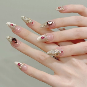 Detalle de uñas postizas de terciopelo rojo con rubíes, perlas y toques de brillo dorado