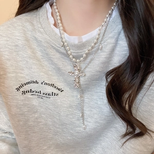 Détail du collier double rang avec pendentif croix texture lave et glands en perles
