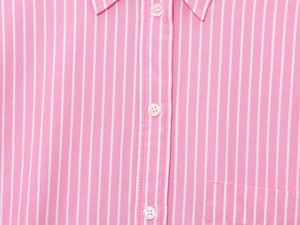 Detail of pink and white vertical stripes on cotton fabric with white resin buttons