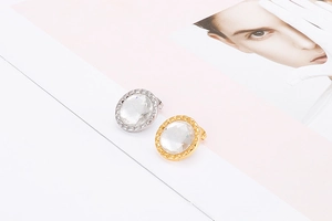 Close-up of sparkling round crystal earrings with gold and silver settings on a white base