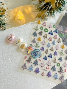 Gros plan de stickers à ongles Noël 3D avec sapins colorés et couronnes festives