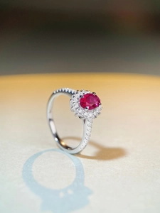 Macro shot of oval red gemstone ring with halo white zircon setting in silver