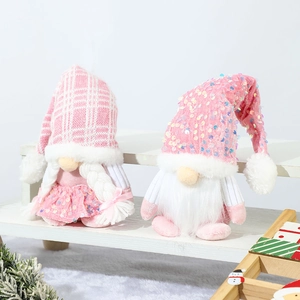 Pink sequin Christmas gnomes with knit hats on white stairs with festive winter decorations