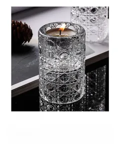 Detailed view of a geometric cut glass candlestick holder with a burning tea light candle