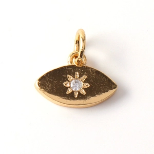 Detail of gold plated eye shaped pendant featuring sunburst texture and cubic zirconia