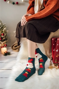 Close-up of thick coral fleece Christmas socks with festive patterns on a cozy background