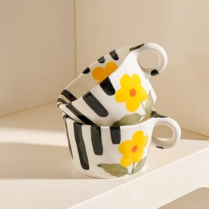 Stacked ceramic mugs featuring hand-painted yellow flowers and black vertical stripes