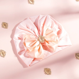 Detail of pink baby turban with a large satin bow and rhinestone jewel embellishment