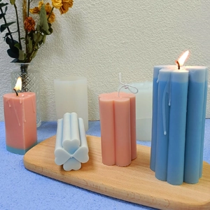 Three-dimensional heart-shaped pillar candles in pastel colors on a wooden tray