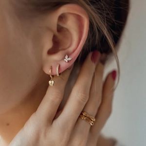 Close-up of a gold jewelry set featuring heart charms, star studs, and textured rings