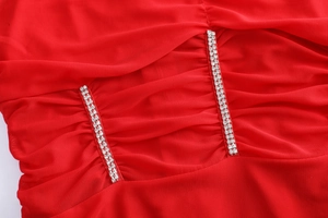 Gros plan sur robe en maille rouge avec bretelles en strass et texture drapée