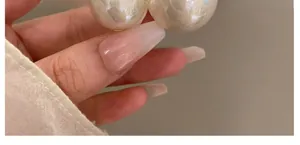 Detail showing high-quality round white pearls on a hair clip held in hand close-up