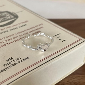 Close-up of a 925 silver twisted heart ring on a vintage box with textured wood base