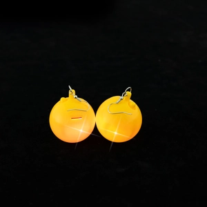 Close-up of yellow glowing disco ball earrings with reflective surface and metal hooks