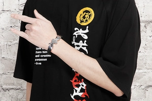 Detail of woven leather bracelet with a silver rabbit charm on a male model's wrist