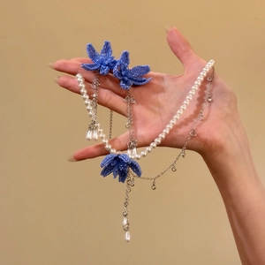 Close-up of elegant blue beaded flower jewelry set with pearls and silver chains