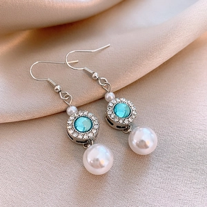 Detailed macro view of silver bow earrings with blue zircon and elegant pearl drop