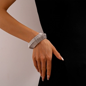 Detail view of silver wide braided cuff bracelet with textured metallic surface finish