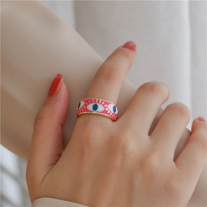 Close-up of a wide pink enamel 18K gold plated eye ring worn on a finger