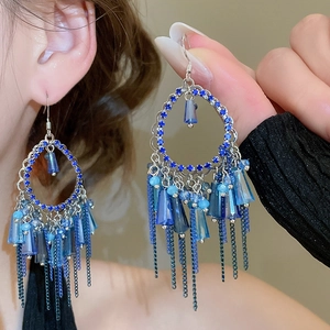 Detailed macro view of bohemian blue crystal drop earrings with metallic chain tassels