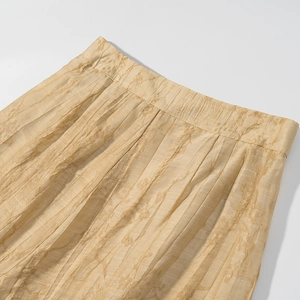 Detailed close-up of champagne jacquard fabric and elastic waistband on casual trousers