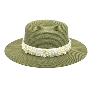 Détail d'un chapeau de paille olive orné de perles élégantes sur un ruban de satin blanc