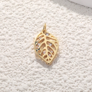 Macro view of a gold leaf pendant with hollow design and clear cubic zirconia stones