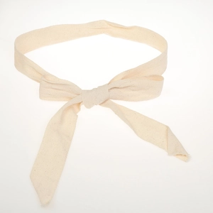 Detail of beige hand-woven cotton linen belt with herringbone pattern tied in a bow