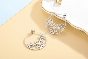 Detail of silver hollow daisy flower charms within large stainless steel hoop earrings
