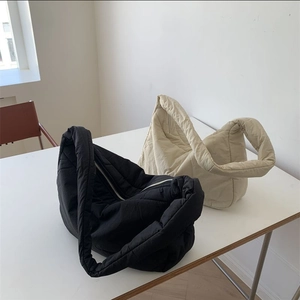 Quilted puffer hobo bags in black and beige displayed on a minimalist white surface